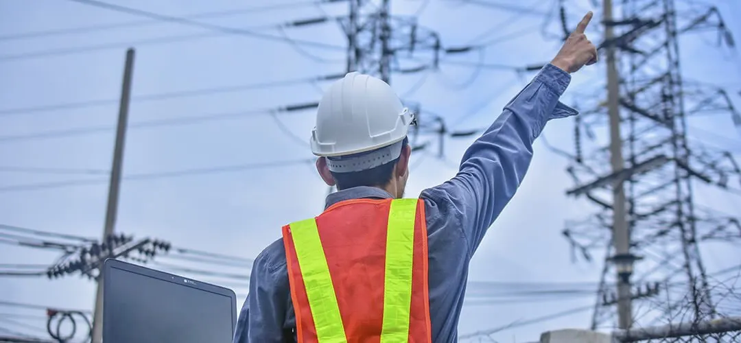 Ingeniero con casco señalando una línea de transmisión eléctrica